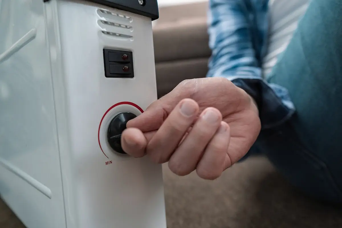 Main réglant le thermostat d'un radiateur à bain d'huile blanc