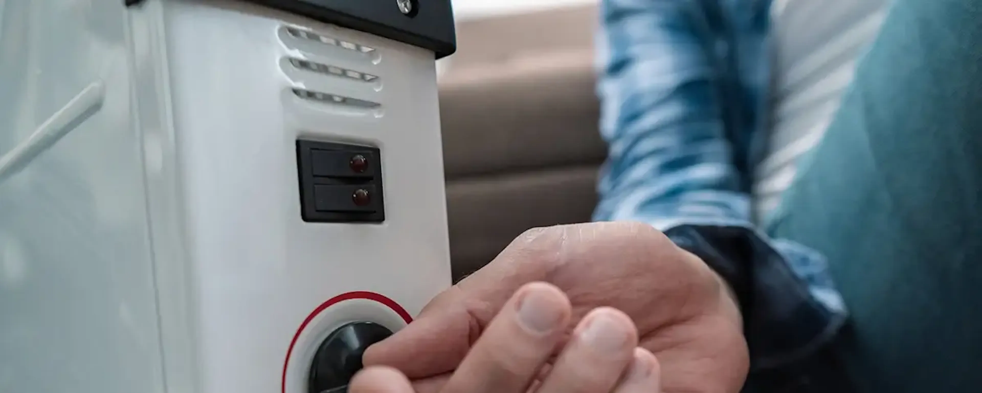 Main réglant le thermostat d'un radiateur à bain d'huile blanc