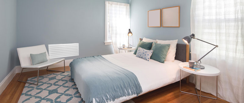 Chambre lumineuse aux murs bleus avec grand lit blanc et parquet