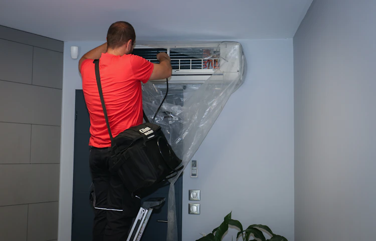 Technicien HomeServe nettoyant et entretenant une climatisation