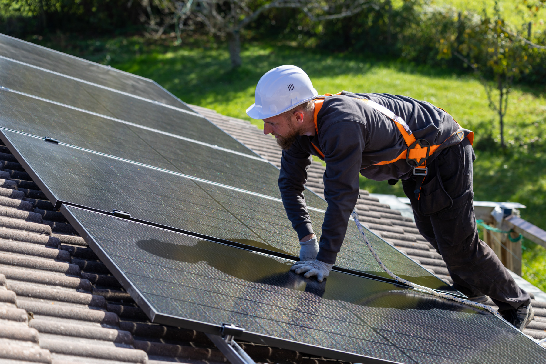Installateur posant des panneaux photovoltaïques sur le toit d'une maison individuelle