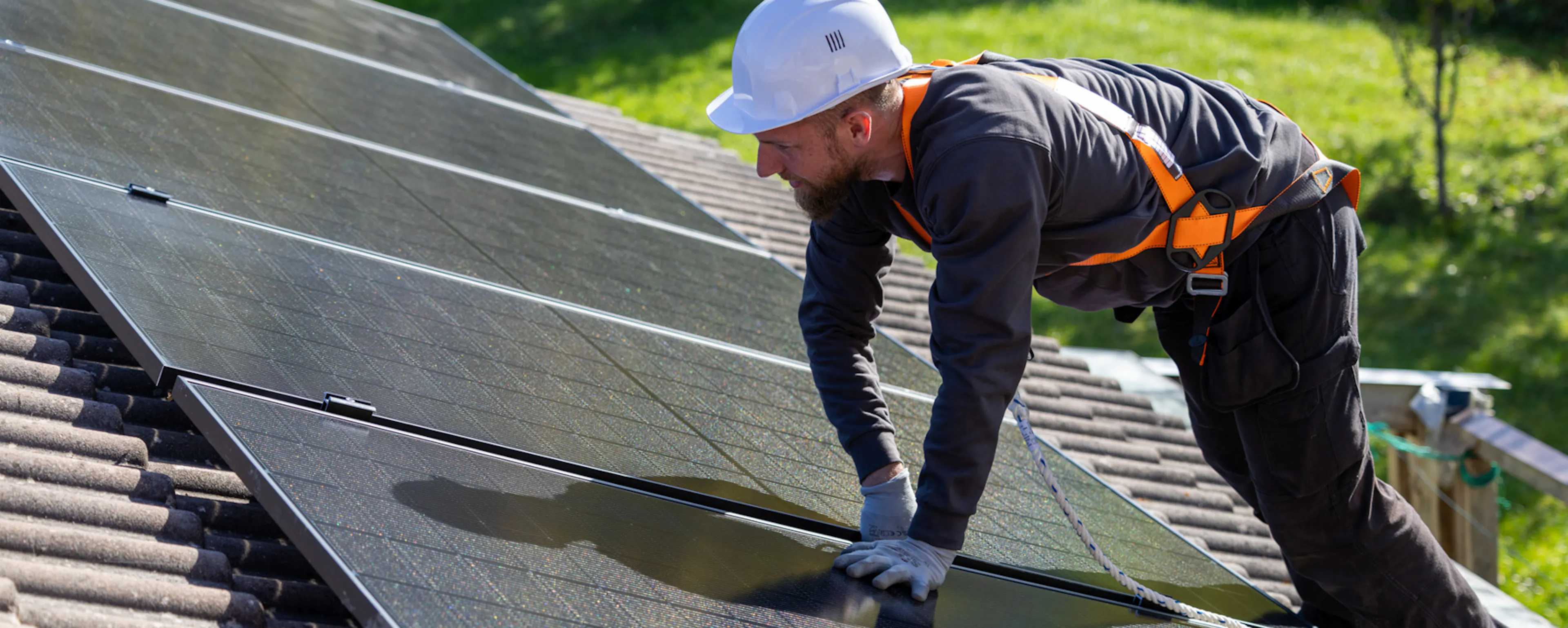 Installateur posant des panneaux photovoltaïques sur le toit d'une maison individuelle