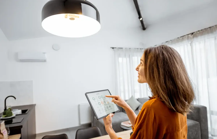 Femme pilotant une climatisation via une tablette dans son salon