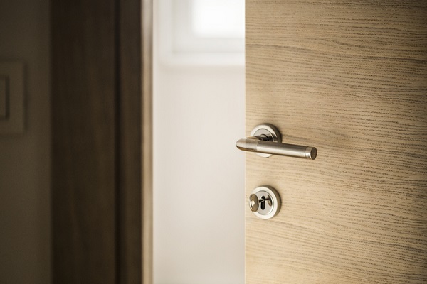 Porte en bois entrouverte avec une poignée et une serrure chromées