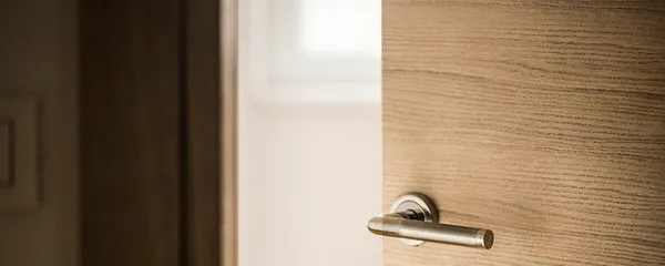 Porte en bois entrouverte avec une poignée et une serrure chromées