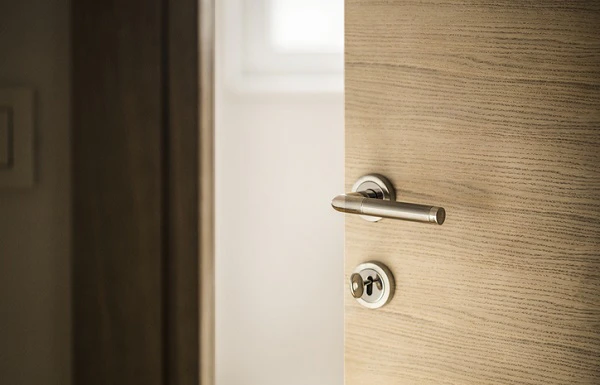 Porte en bois entrouverte avec une poignée et une serrure chromées