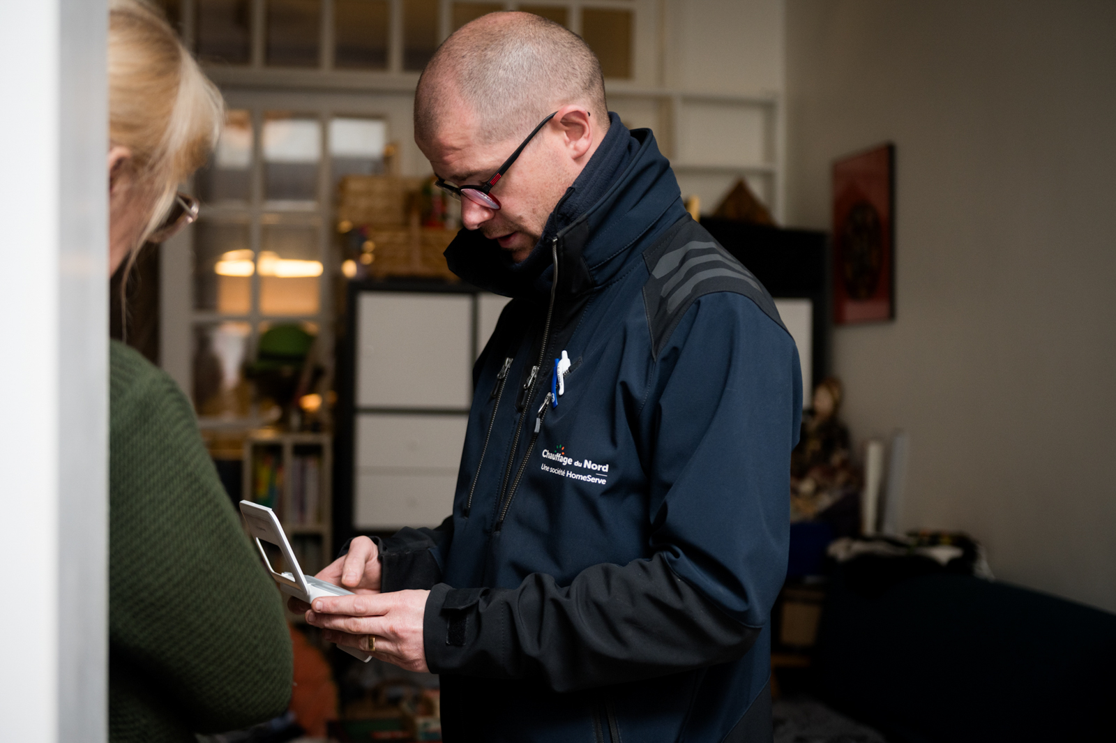 Technicien chaudière HomeServe conseillant une cliente quant à son thermostat