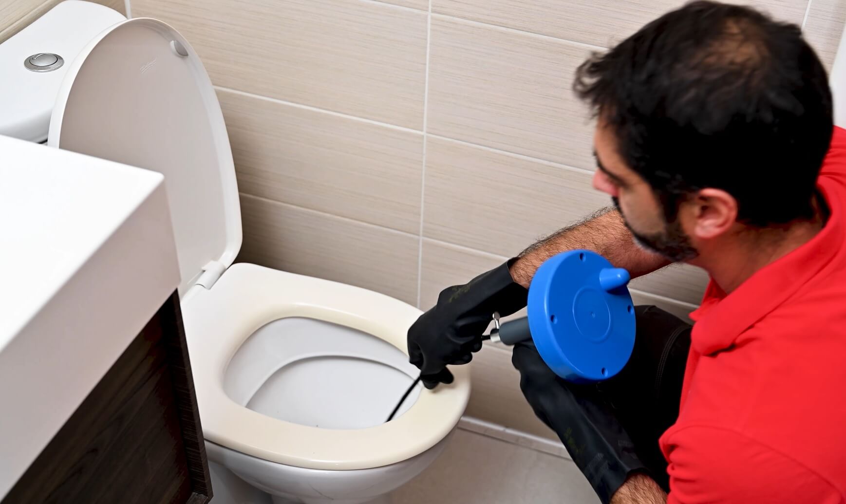Technicien utilisant un furet pour déboucher des toilettes