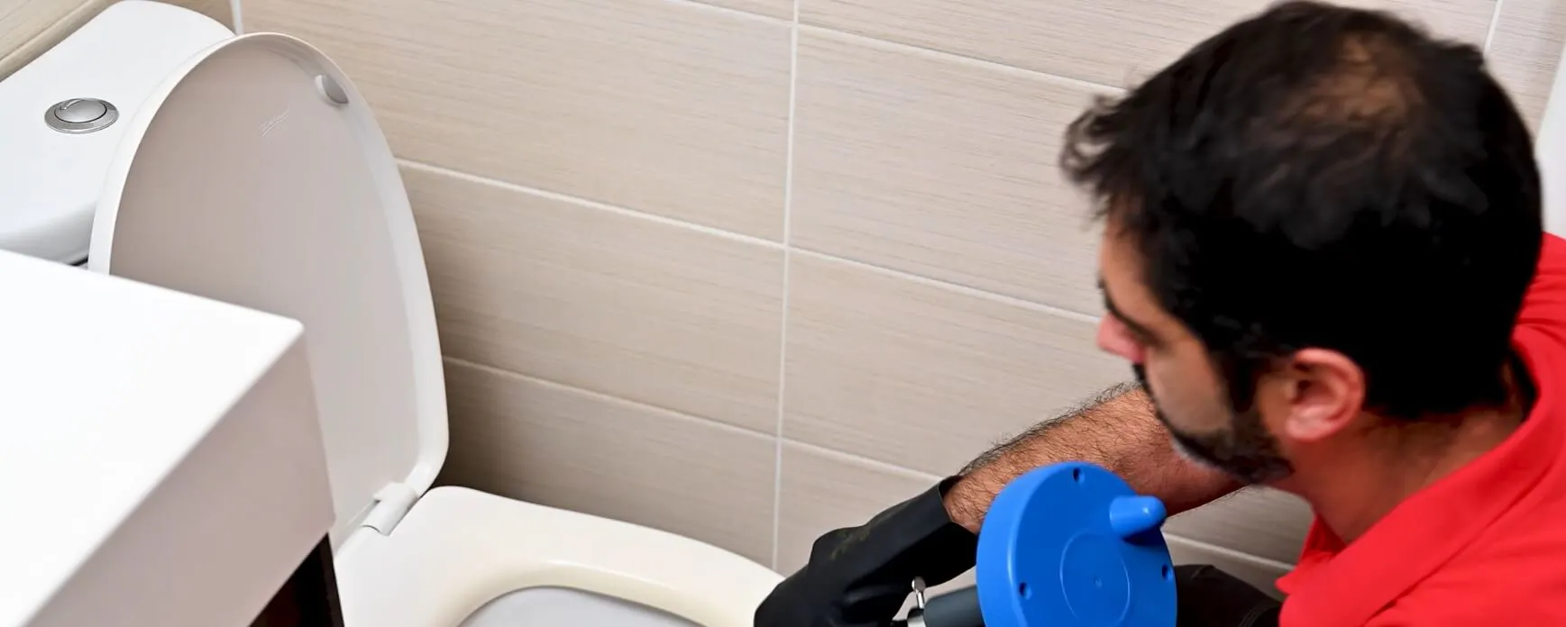 Technicien utilisant un furet pour déboucher des toilettes