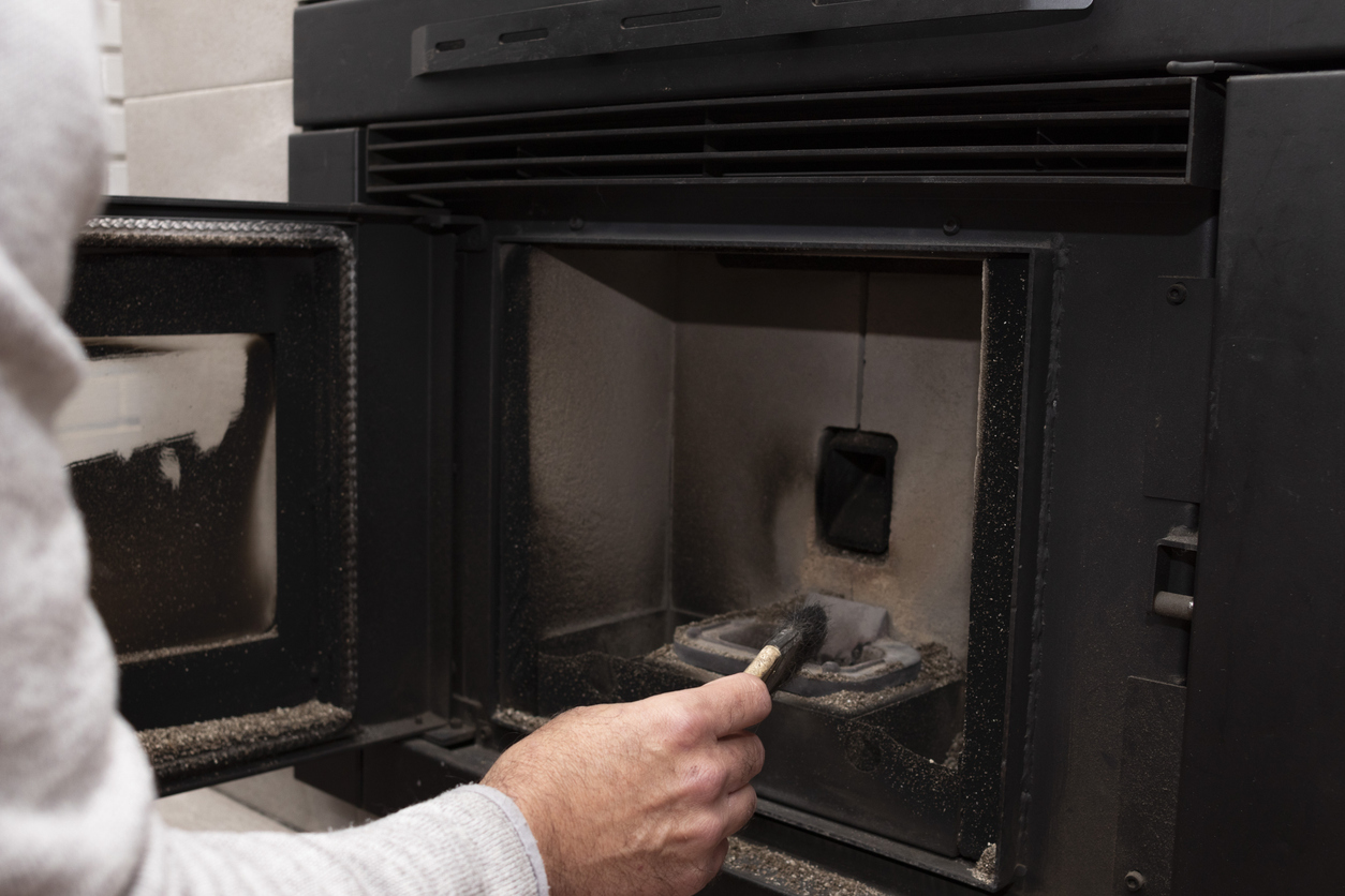 Technicien chauffagiste inspectant la chambre de combustion d'un poêle à pellets