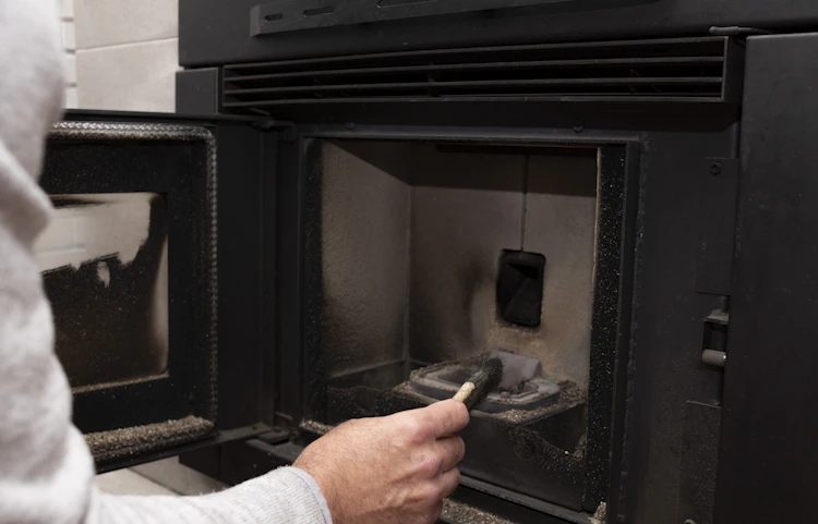 Technicien chauffagiste inspectant la chambre de combustion d'un poêle à pellets