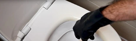 Main gantée utilisant une ventouse pour déboucher des toilettes