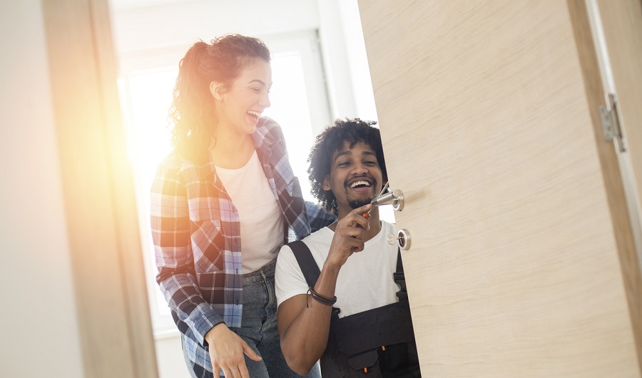 Couple souriant devant une porte d'entrée, homme tenant des clés