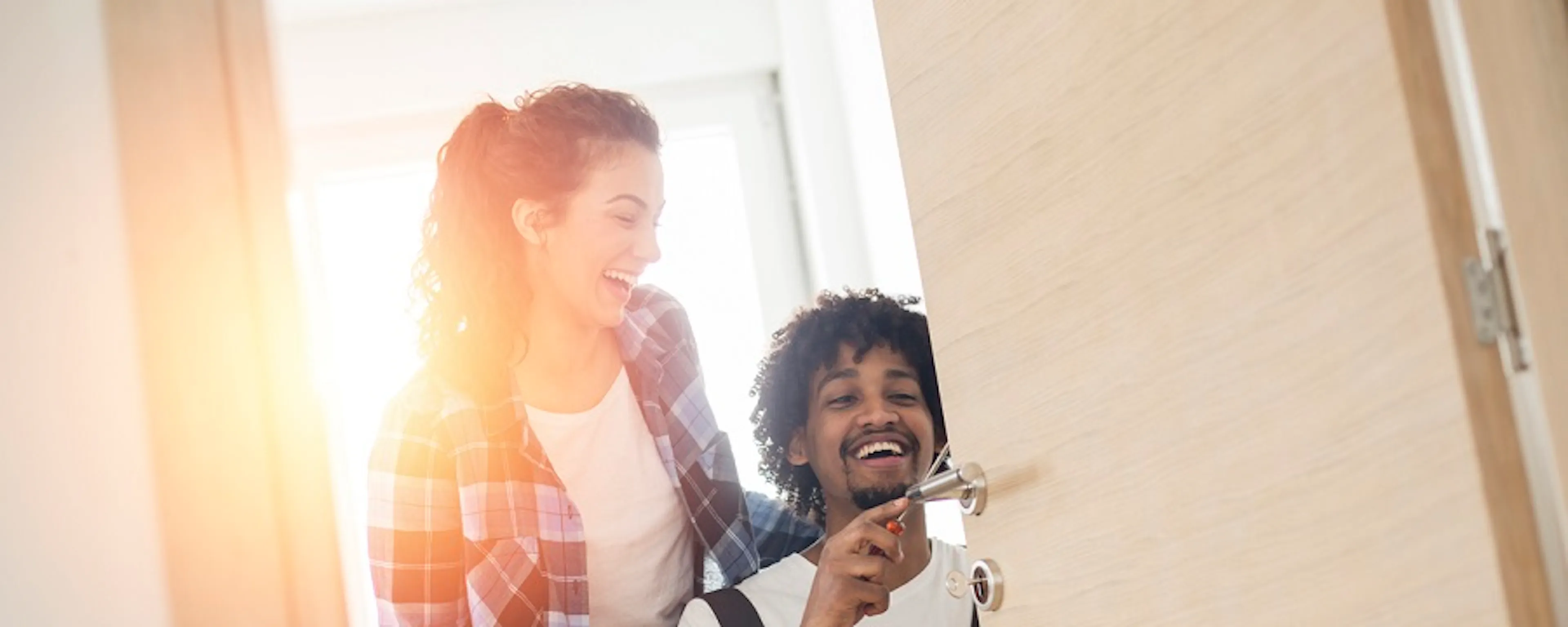 Couple souriant devant une porte d'entrée, homme tenant des clés