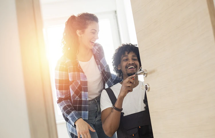 Couple souriant devant une porte d'entrée, homme tenant des clés