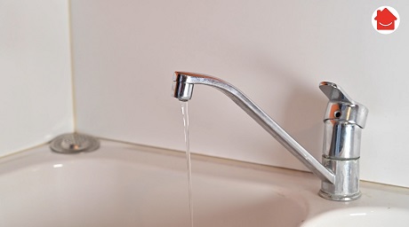 Robinet de cuisine chromé coulant de l'eau dans un évier blanc