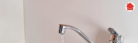 Robinet de cuisine chromé coulant de l'eau dans un évier blanc