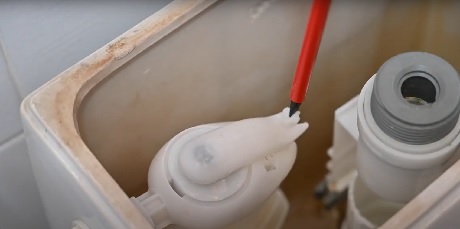 Intérieur d'un réservoir de toilettes avec mécanisme de chasse visible