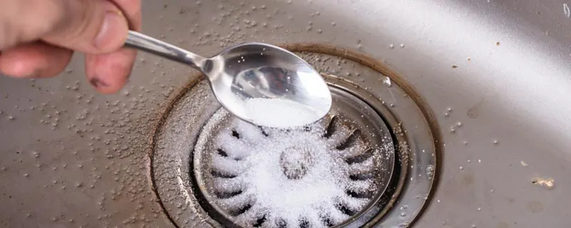 Main versant du bicarbonate de soude dans un siphon d'évier métallique