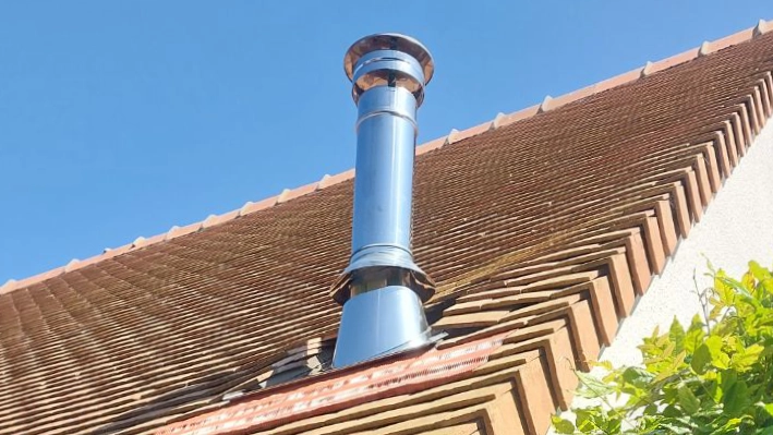Conduit d'évacuation des fumées d'un poêle à bois sur un toit en Normandie