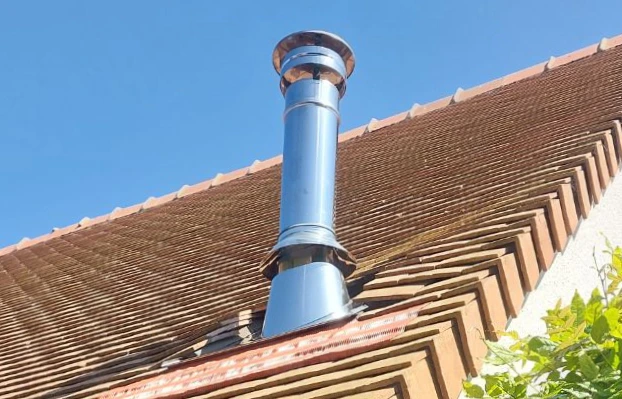 Conduit d'évacuation des fumées d'un poêle à bois sur un toit en Normandie
