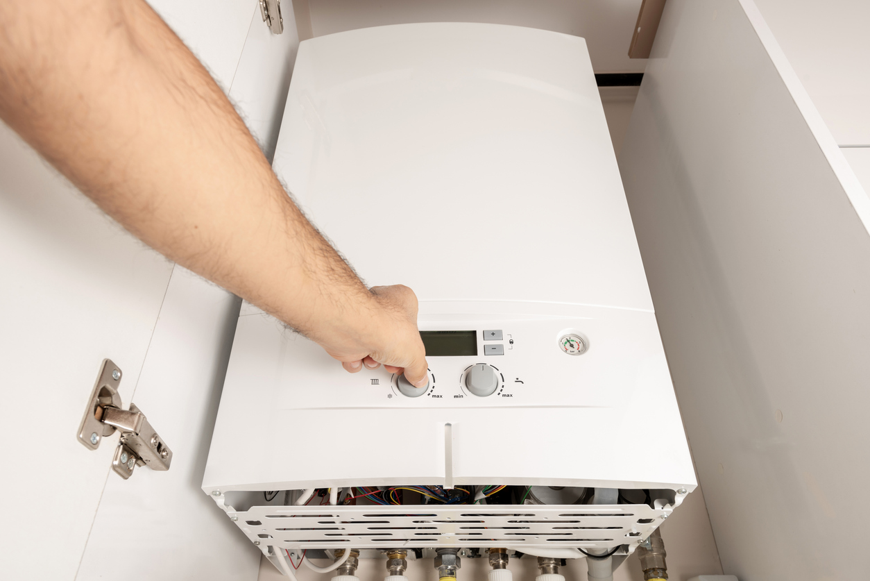 Technicien chauffagiste vérifiant les réglages d'une chaudière gaz et analysant les données de consommation énergétique