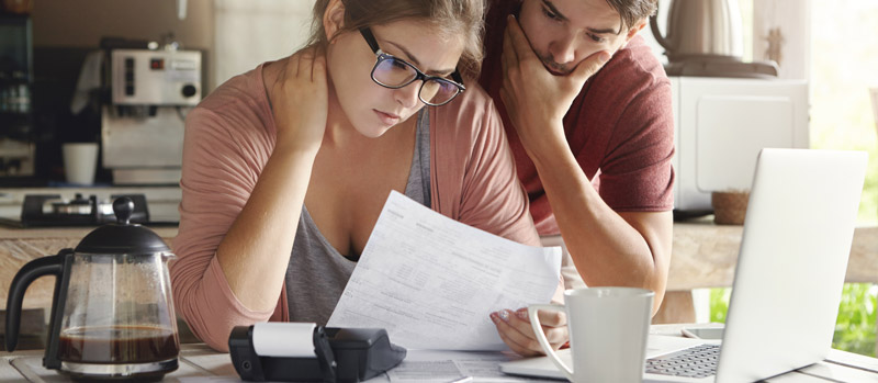 Couple stressé examinant des factures devant un ordinateur portable