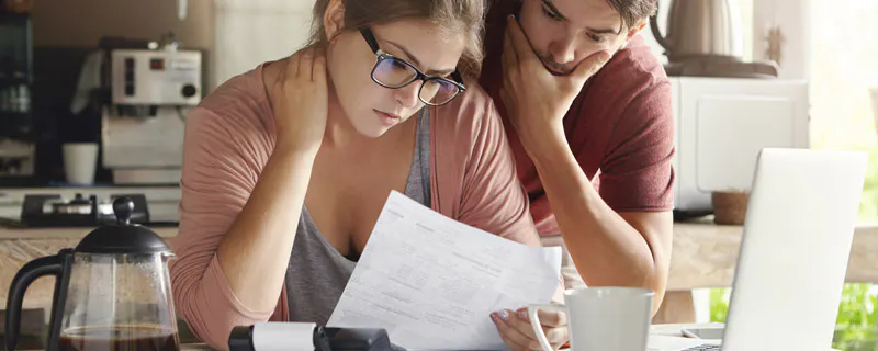 Couple stressé examinant des factures devant un ordinateur portable