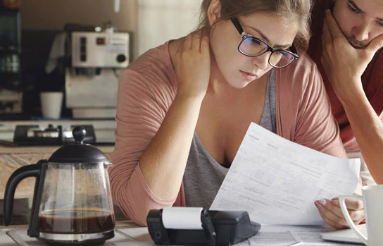 Couple stressé examinant des factures devant un ordinateur portable