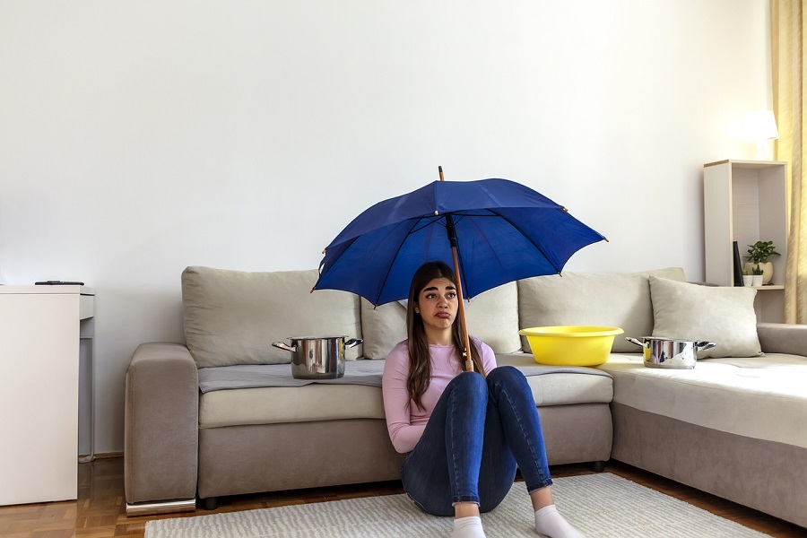Femme assise sous un parapluie bleu dans un salon avec bassines