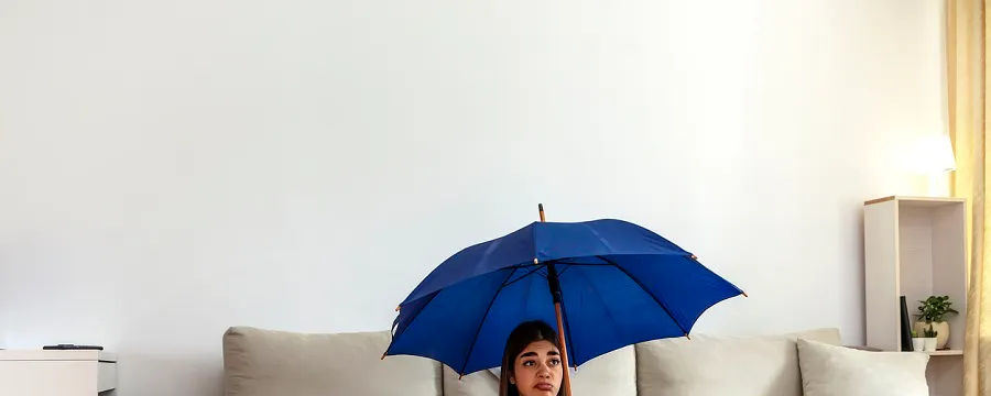 Femme assise sous un parapluie bleu dans un salon avec bassines