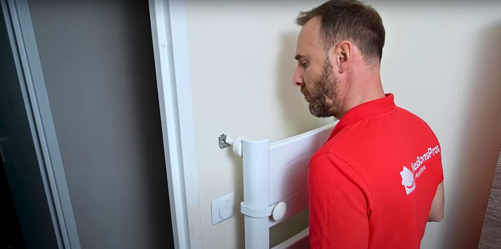 Technicien en rouge installant un radiateur blanc contre un mur