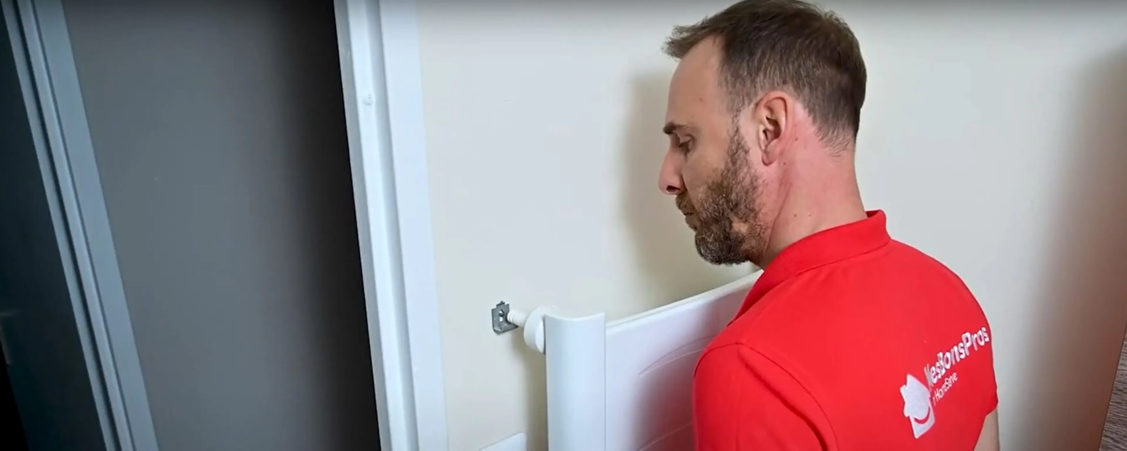 Technicien en rouge installant un radiateur blanc contre un mur