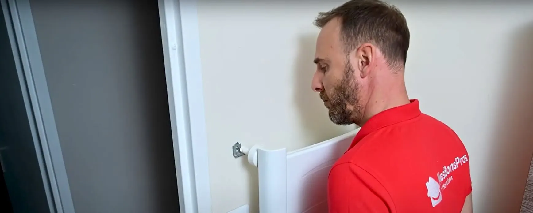 Technicien en rouge installant un radiateur blanc contre un mur