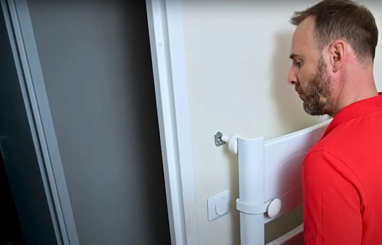 Technicien en rouge installant un radiateur blanc contre un mur