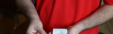 Mains en rouge insérant une pile dans un détecteur de fumée