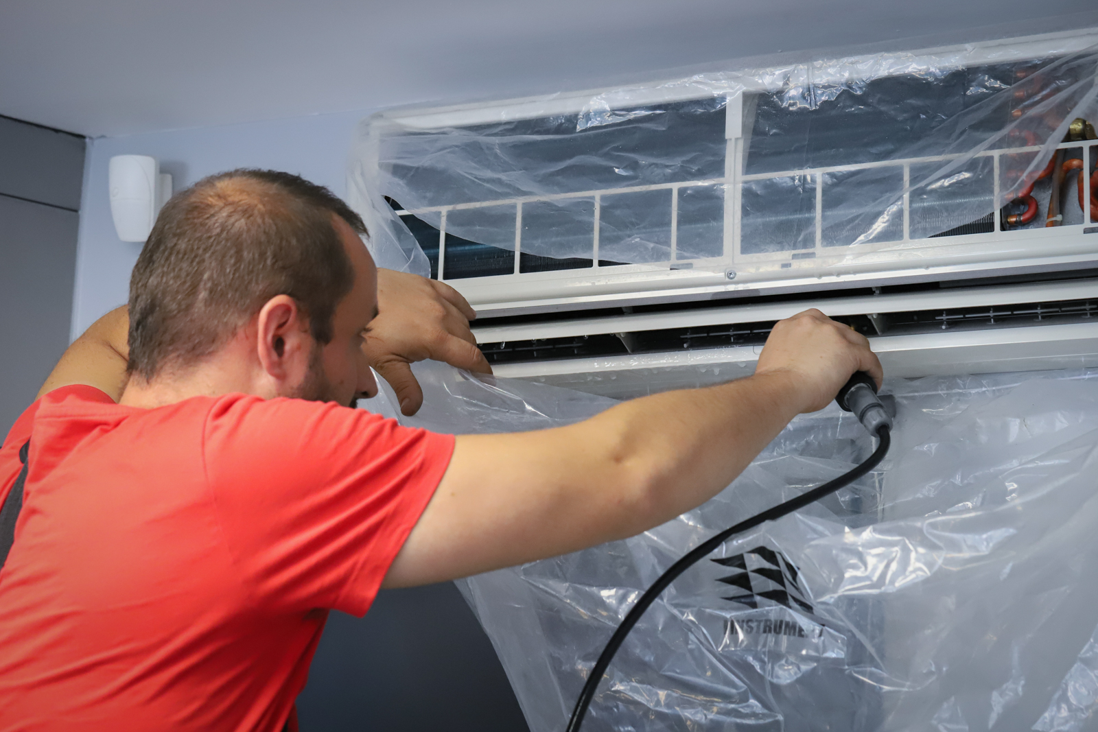 Un technicien de maintenance climatisation en train de nettoyer l'intérieur d'une unité de climatisation