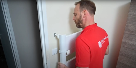 Technicien en polo rouge inspectant une canalisation murale blanche