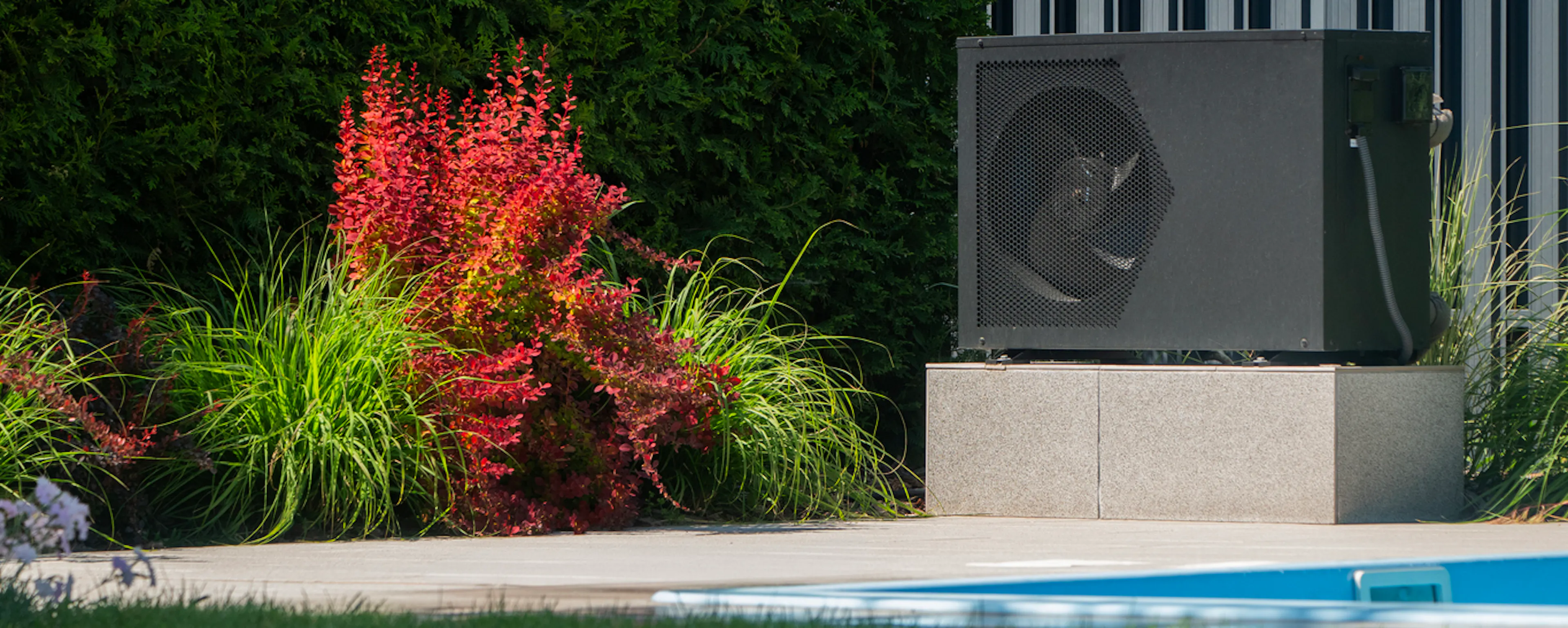 Installation moderne d'une pompe à chaleur pour piscine dans un jardin paysager