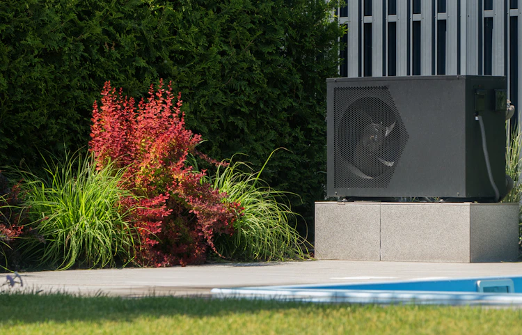 Installation moderne d'une pompe à chaleur pour piscine dans un jardin paysager