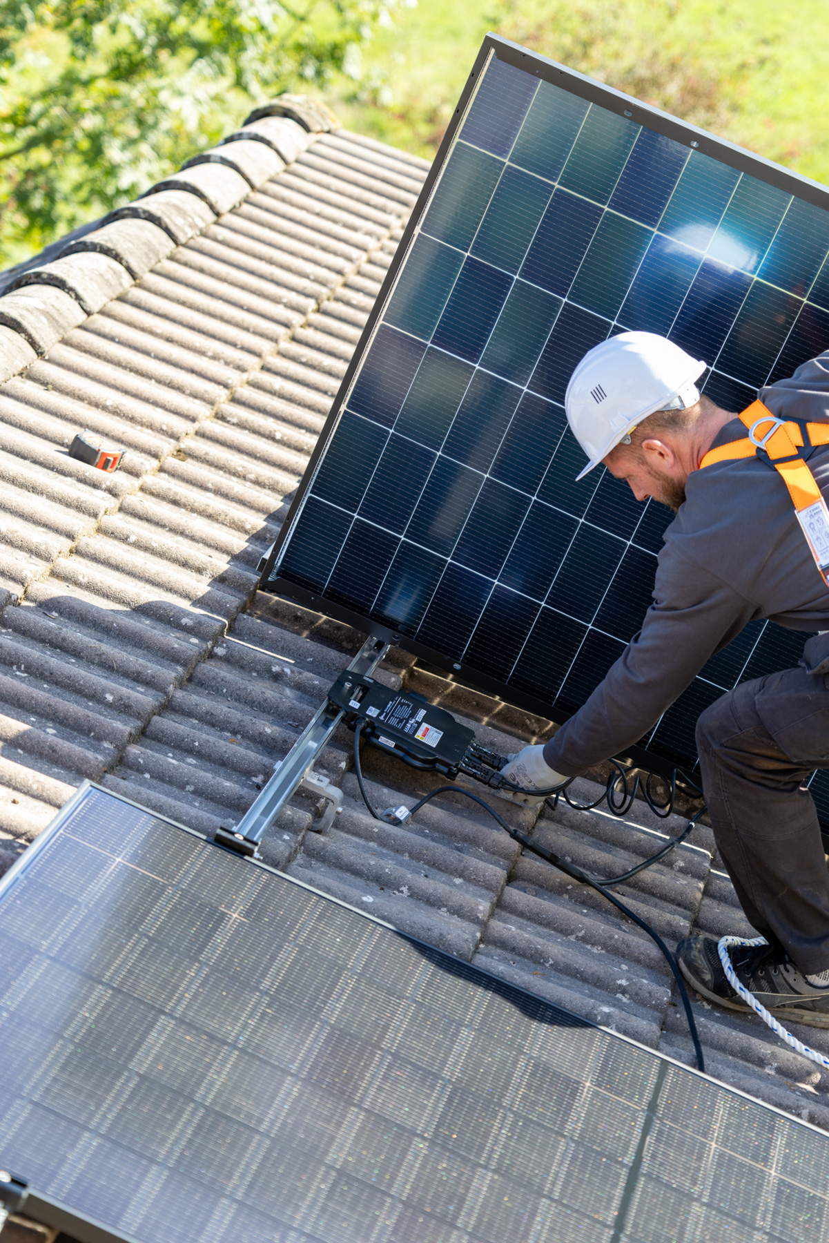 Technicien en toiture câblant un micro-onduleur lors de l'installation de panneaux solaires photovoltaïques
