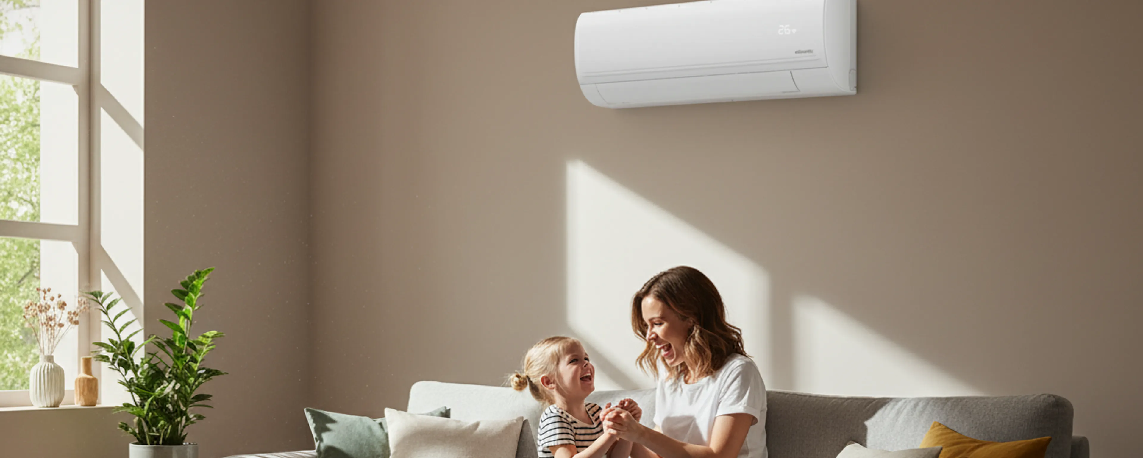 Une mère et sa fille jouent dans le salon lumineux de leur maison, sur le mur derrière elles, un climatiseur Atlantic Murao Smart blanc mat