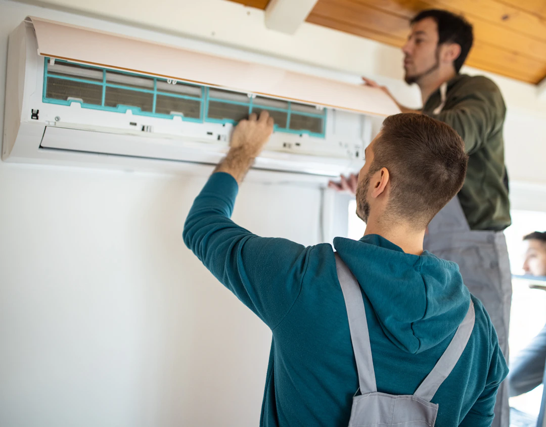 Deux techniciens, en train d'installer une climatisation près de Coutance dans la Manche