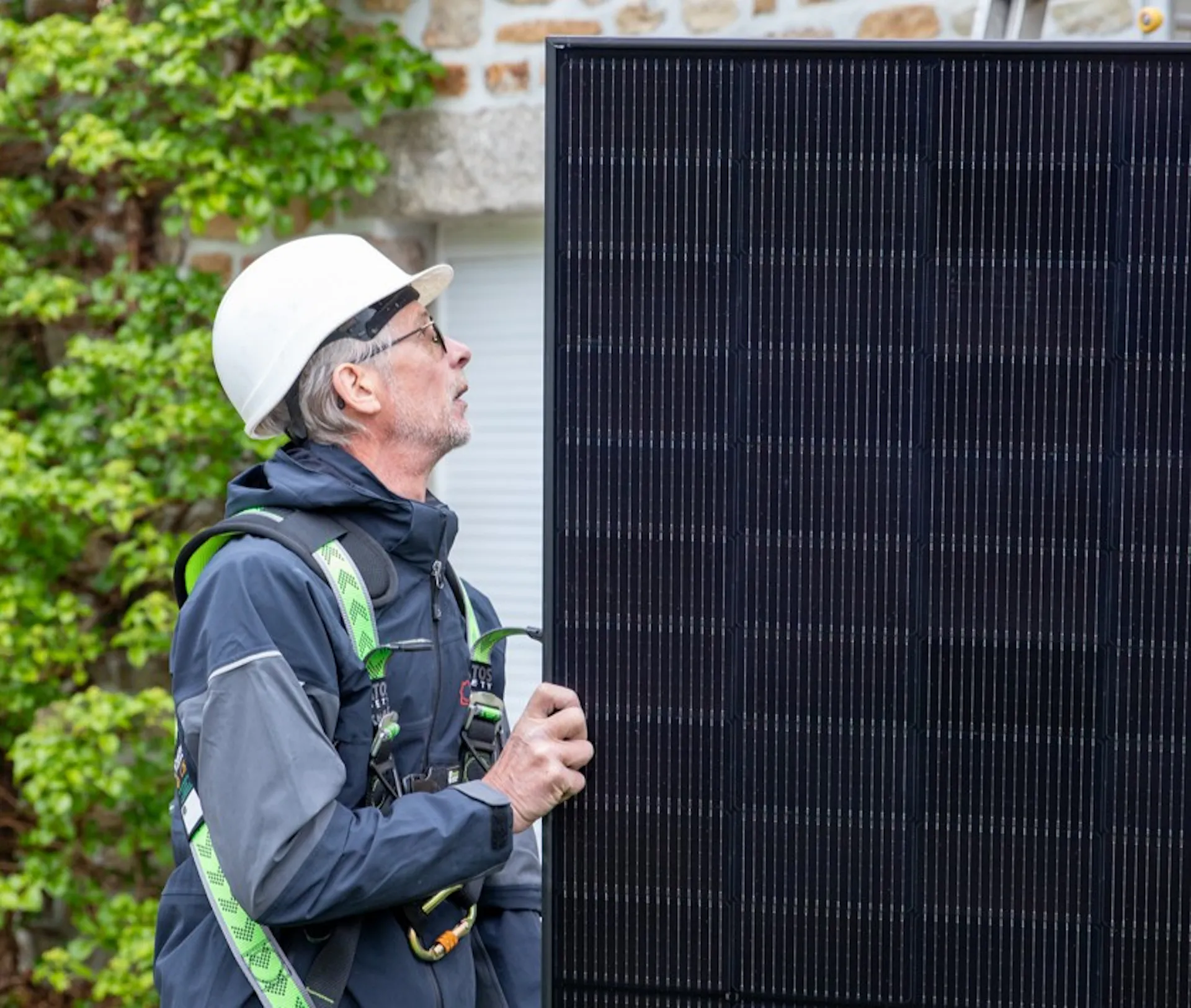 Technicien électricien manipulant un panneau photovoltaïque sur un chantier d'installation VIK Energies
