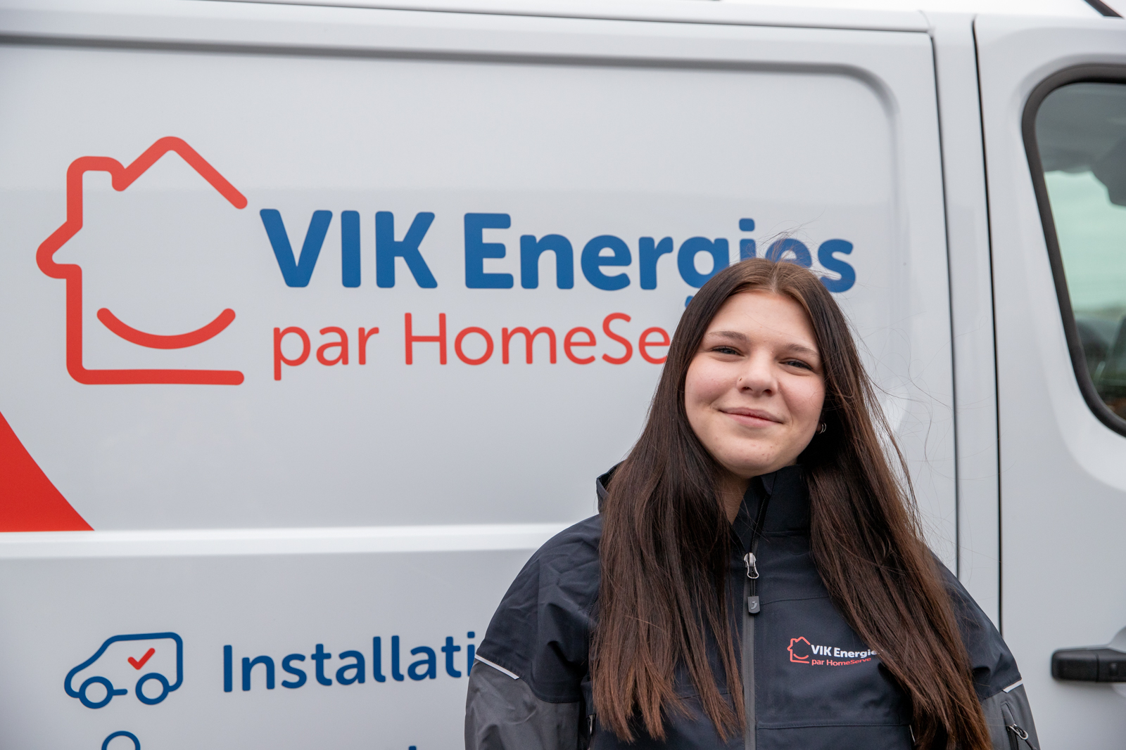 Une technicienne VIK Energies pose devant un camion de l'entreprise avant une intervention chez un client