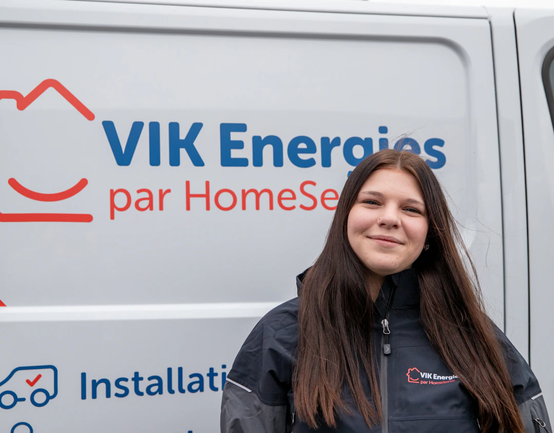 Une technicienne VIK Energies pose devant un camion de l'entreprise avant une intervention chez un client