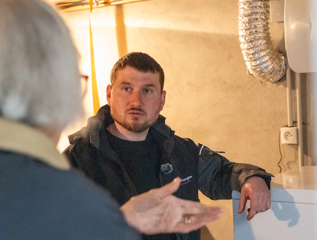 Un technicien VIK Energies répond aux questions d'une cliente à propos de sa chaudière