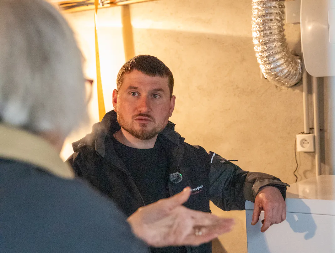 Un technicien VIK Energies répond aux questions d'une cliente à propos de sa chaudière