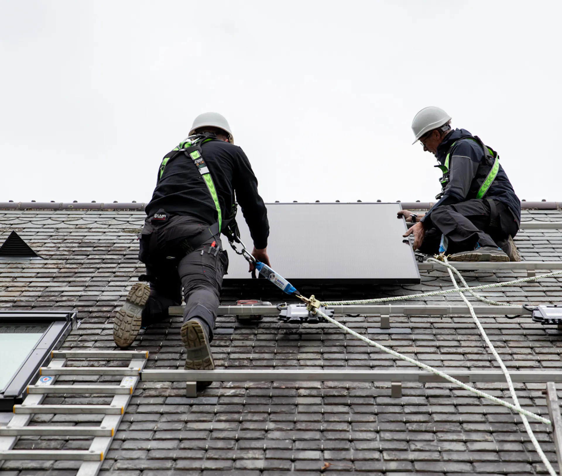 Deux électriciens VIK Energies en train de procéder à l'installation de panneaux solaires en toiture d'une maison normande