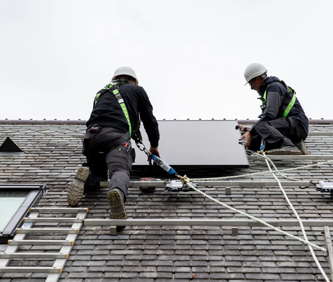 Deux électriciens VIK Energies en train de procéder à l'installation de panneaux solaires en toiture d'une maison normande